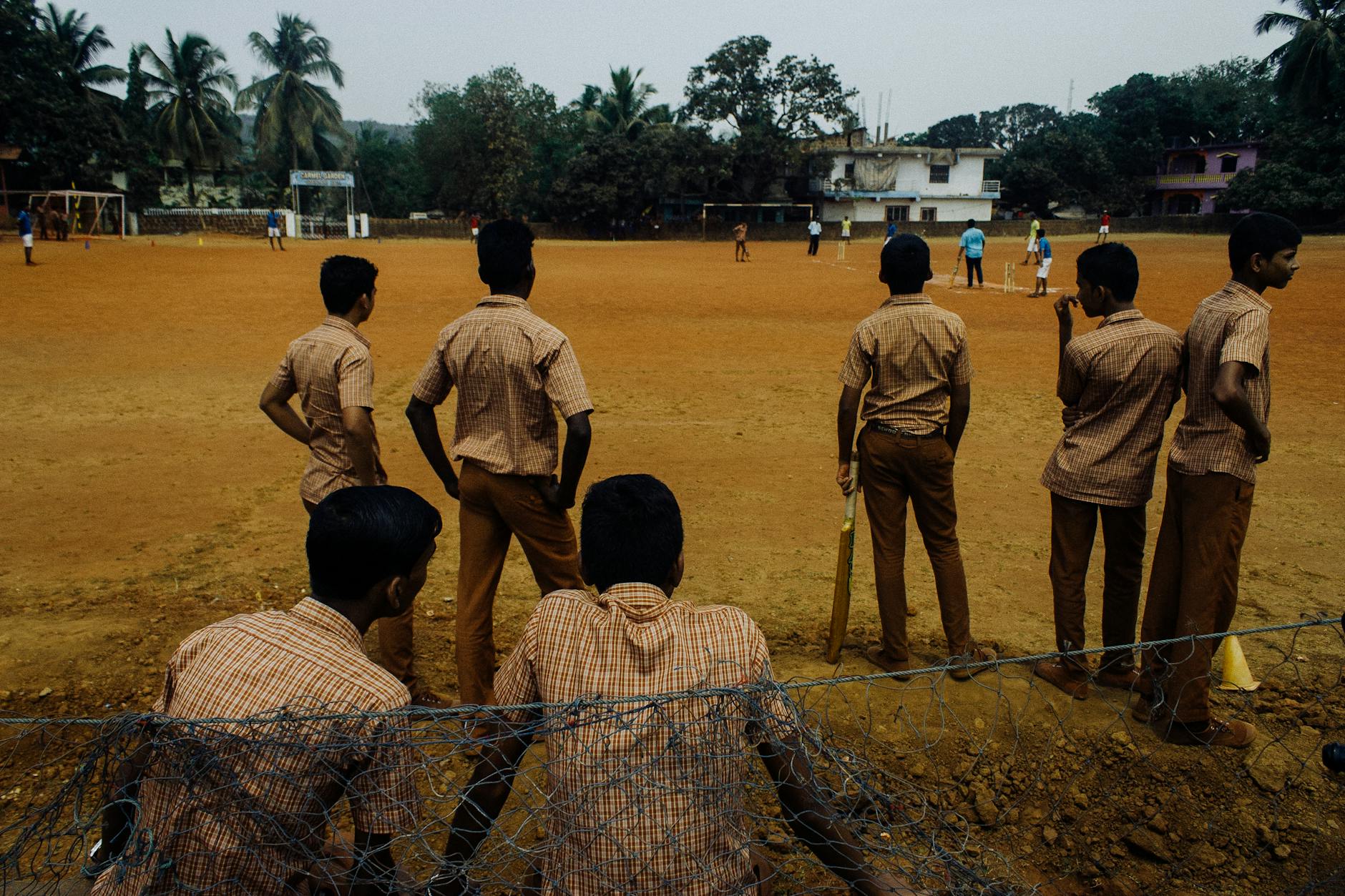 students on brown field near fence